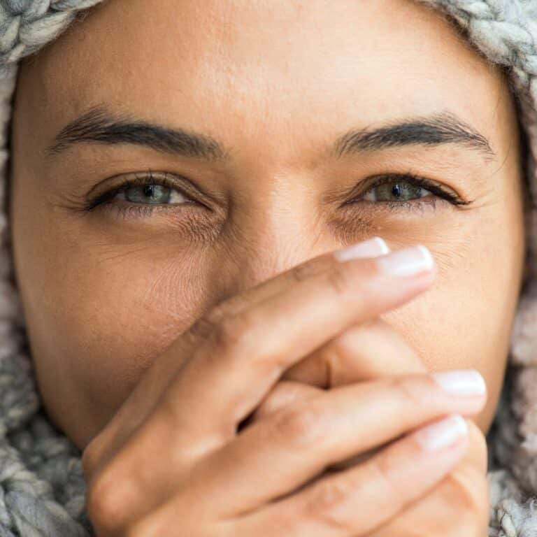 Woman blowing into hands for warmth on a cold day