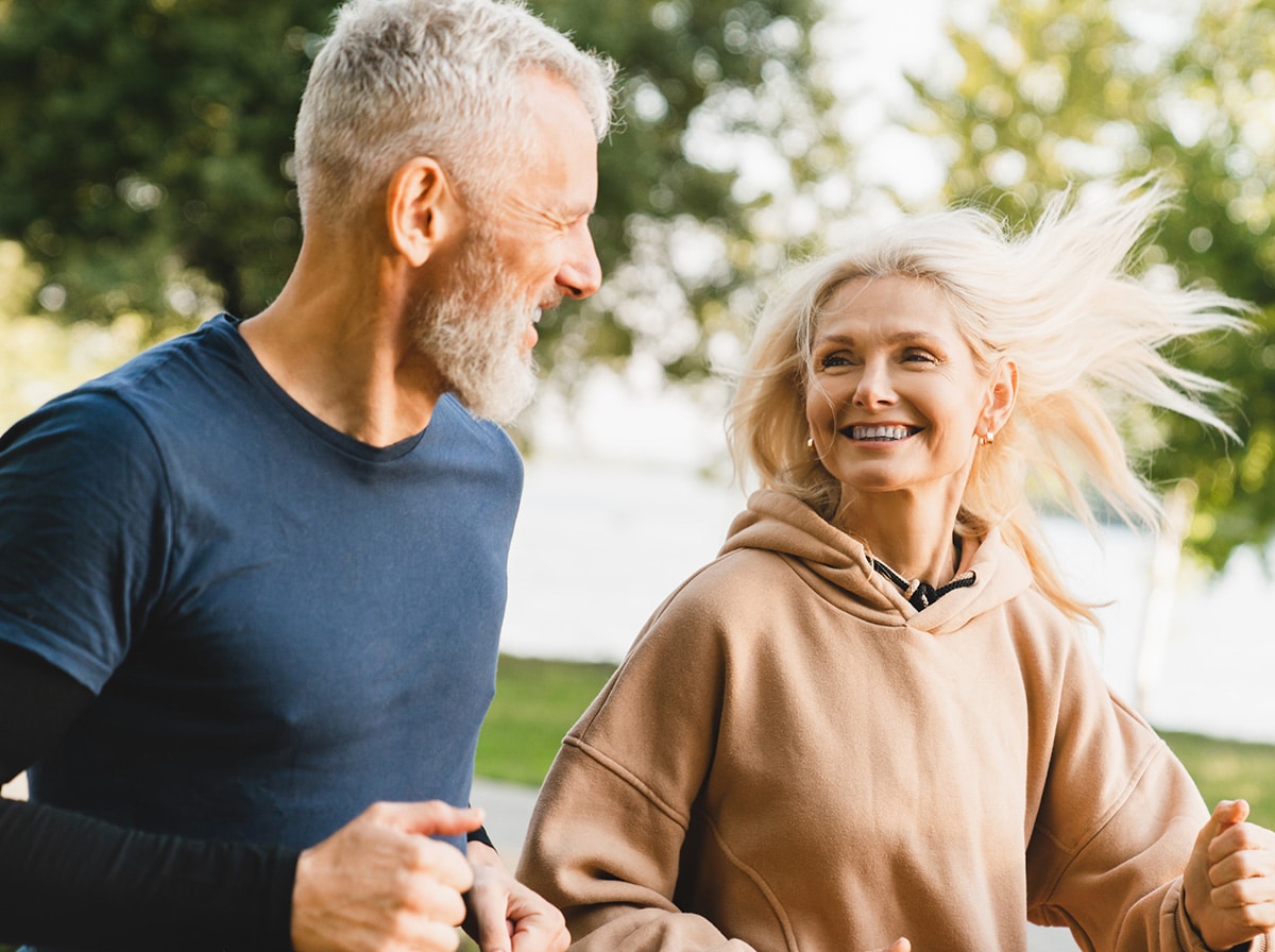 Mature middle aged senior couple running together in the park